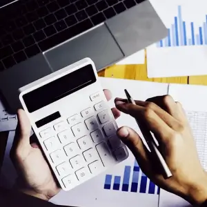 Person using calculator while holding pen in right hand