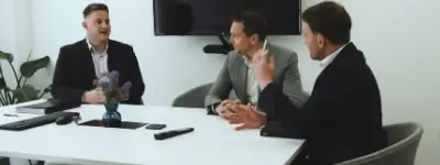 Three men talking to each other around a meeting room table