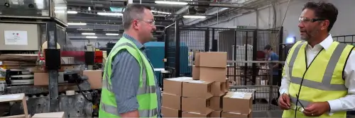 Two men with high visibility jackets speaking to one another