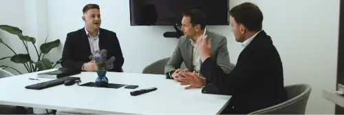 Three men talking to each other around a meeting room table