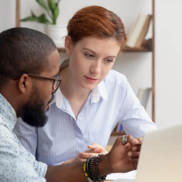 Man with glasses pointing at laptop while woman looks on