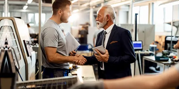 Men with notepads shaking each others hand inside office