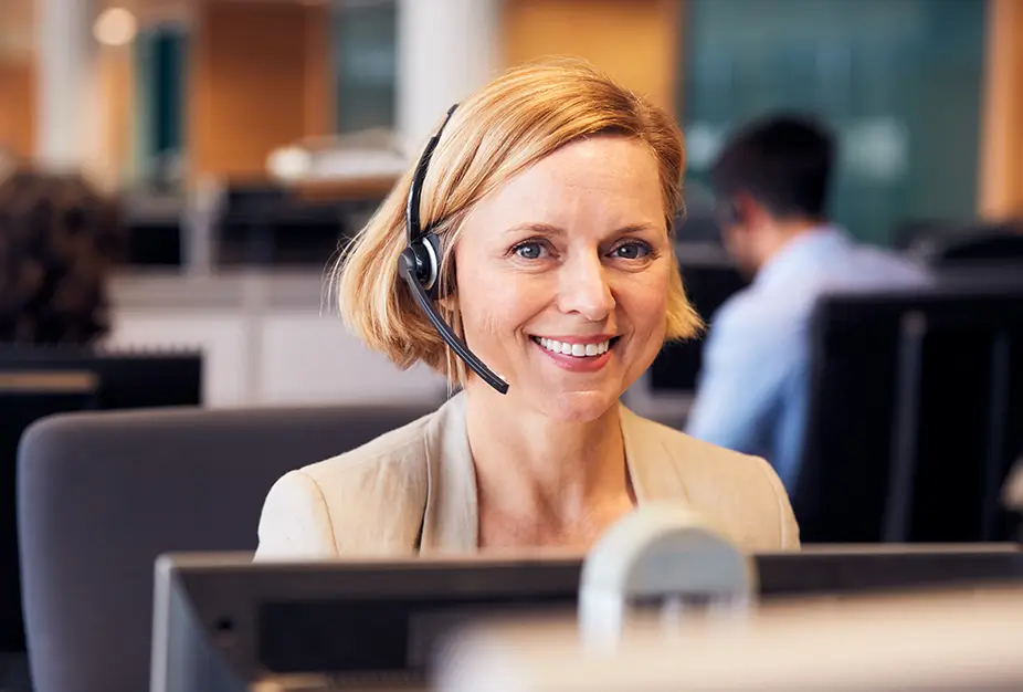 Woman with headset smiling while sat at office desk