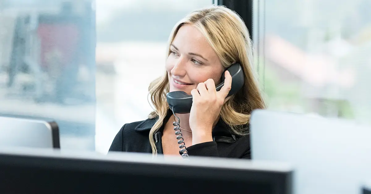 Woman smiling while sitting down with phone up to left ear