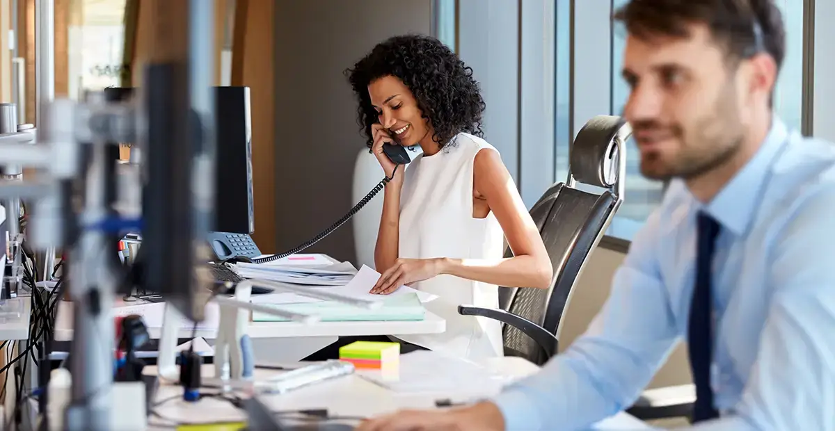 Woman smiling while using telephone and flicking through notes