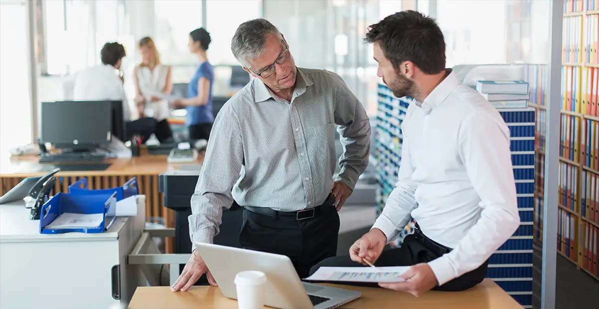 Two office workers stood up looking at notes together