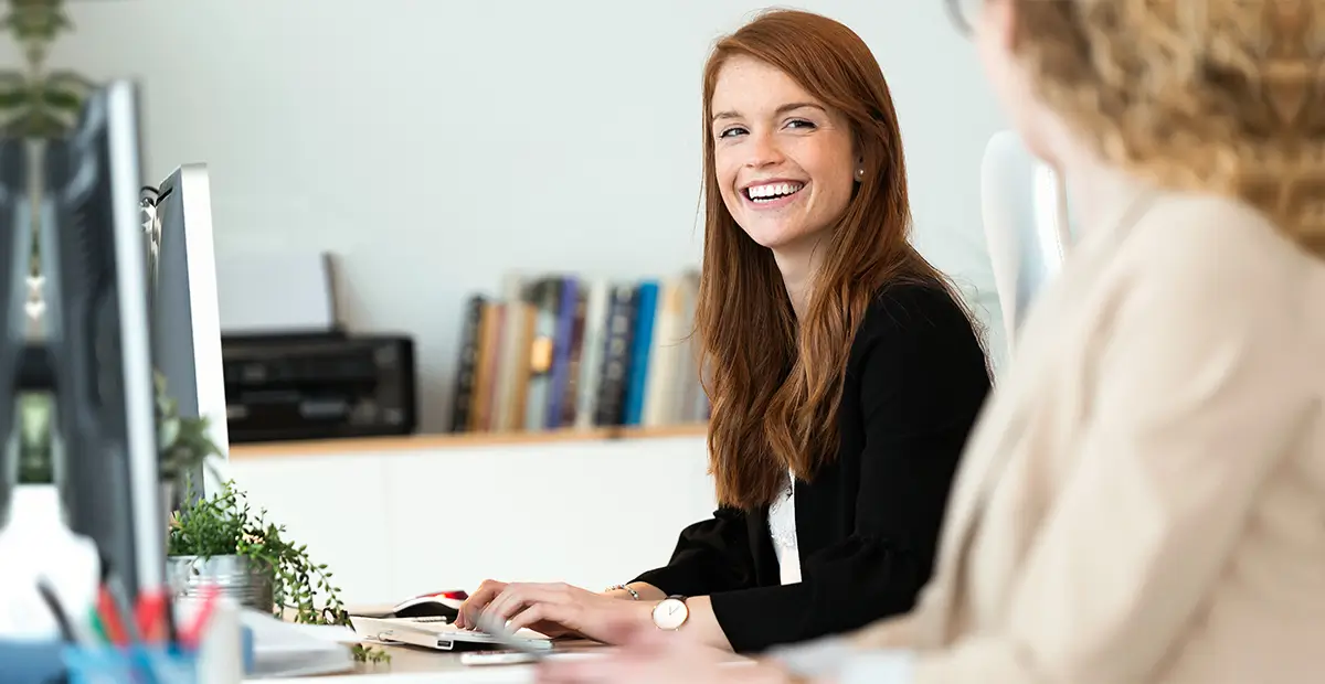 Woman smiling while looking to her left and typing