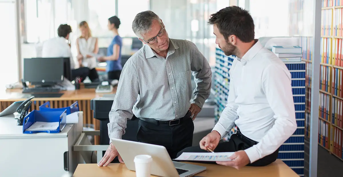 Two businessmen standing up while talking to one another in office