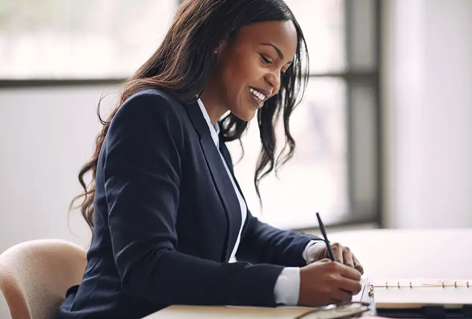 Businesswoman smiling while writing notes in an office