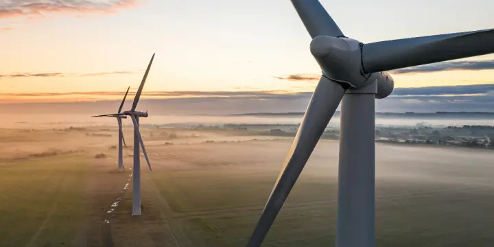 Three wind turbines in rural landscape at dusk