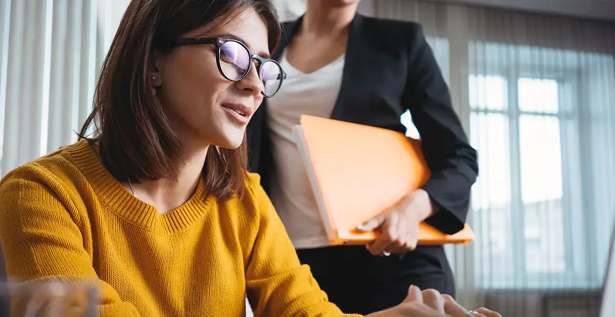 Woman with glasses typing on laptop at desk