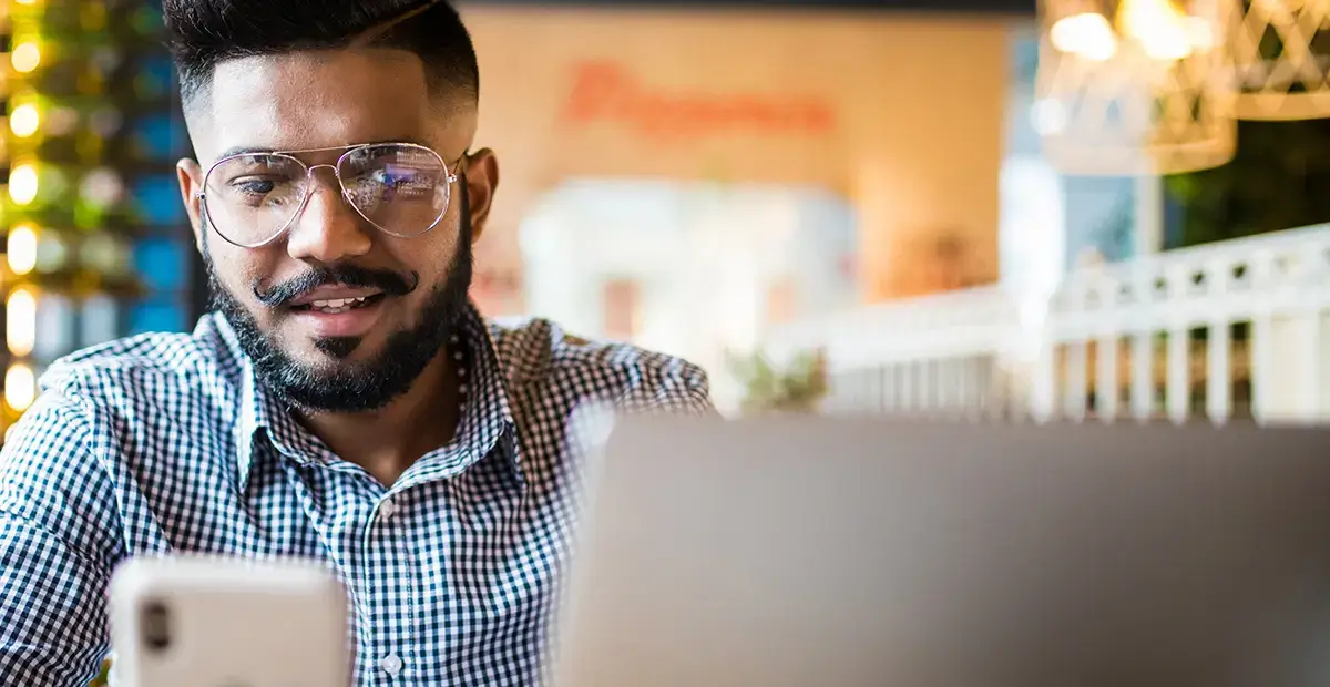 Man with glasses smirking while looking down at mobile phone